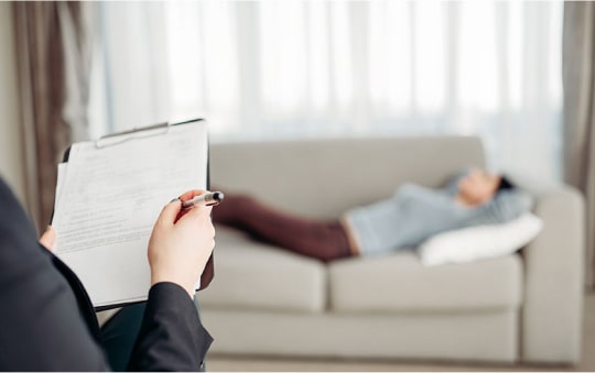 Девушка лежит на диване во время приема психолога